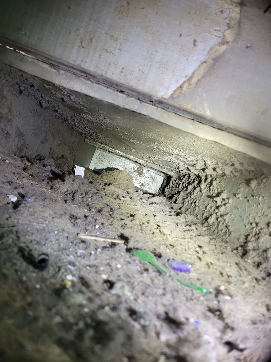 Inside a home air duct before cleaning, coated with thick dust and debris