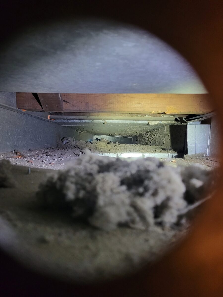 Inside a St. Louis home's air duct before treatment, coated in dark buildup