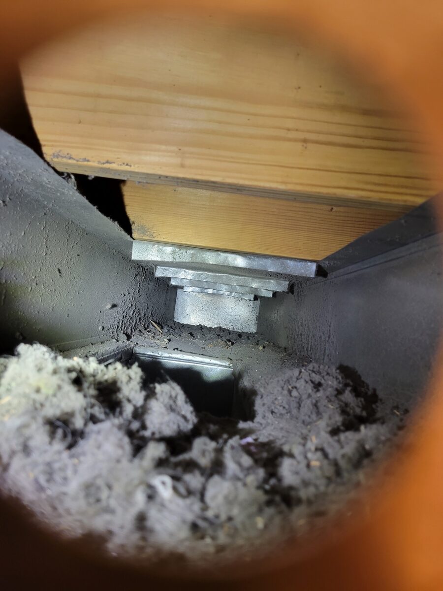Inside a St. Louis home air duct before cleaning, coated in thick gray dust and debris
