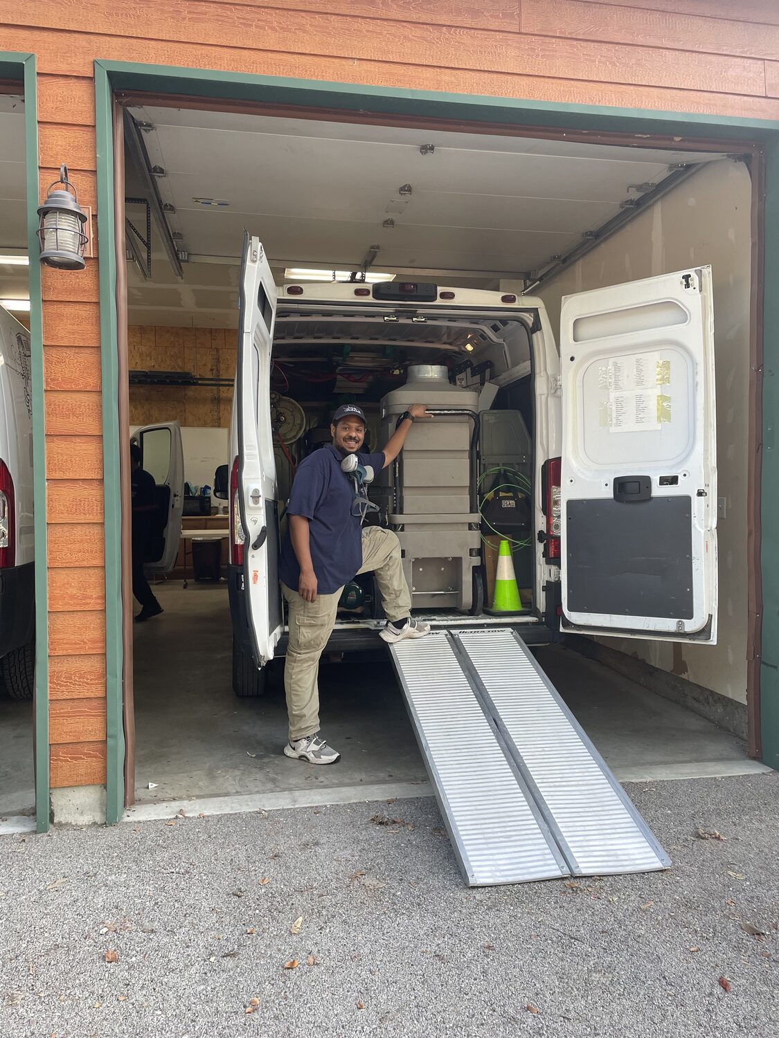 A uniformed SafeAir Duct Care technician at the back of a fully equipped service van on a job in the St. Louis area